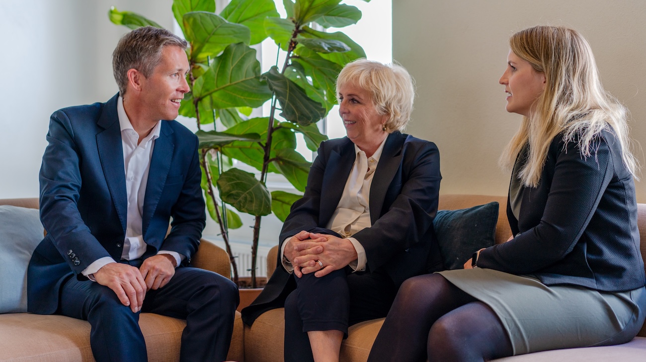 Tre av Econas advokater i samtale med grønn plante i bakgrunnen.