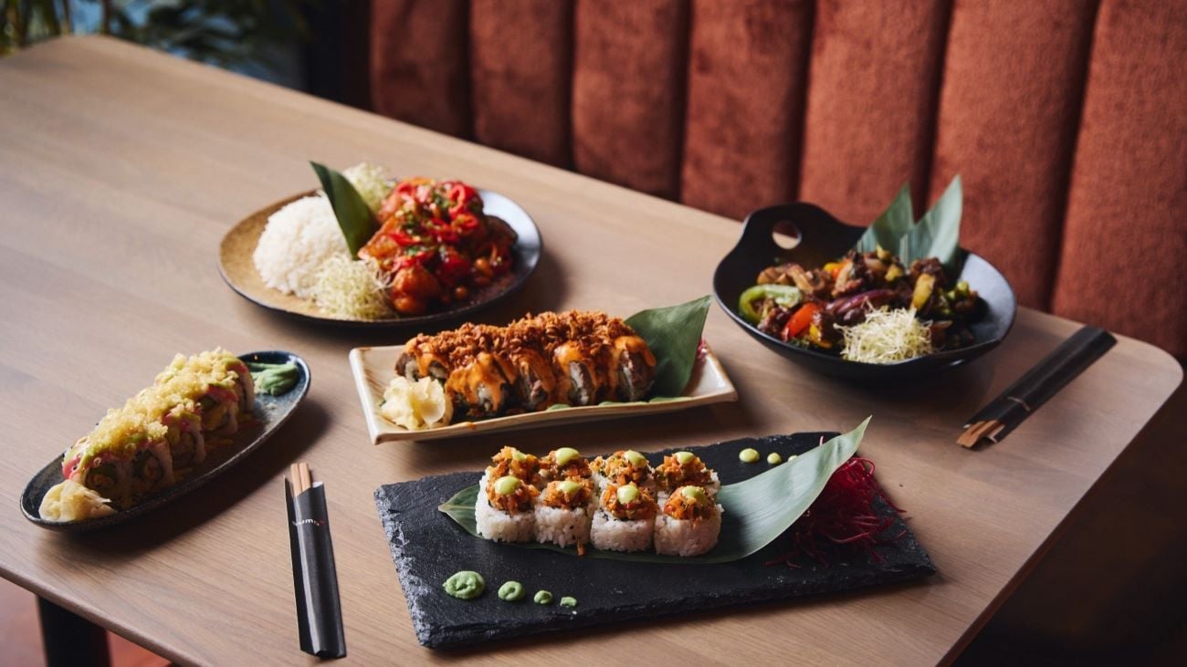 Et utvalg delikate asiatisk-inspirerte retter, inkludert sushi og wok, servert på et stilrent restaurantbord.