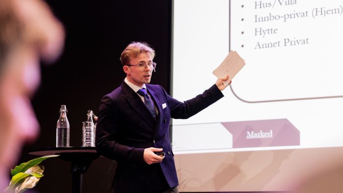 Ung mann som presenterer et case foran publikum og juryen under NM i økonomi 2024.