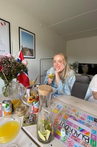 Jente ved et stuebord med flagg, blomster og drikke