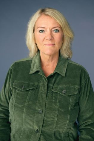 Portrettfoto av kvinne med kort, lyst hår og grønn skjorte. Grå bakgrunn. 