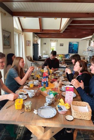 En familie som spiser frokost rundt et langbord.