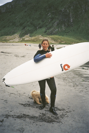 Ung kvinne som holder et surfebrett på en sandstrand