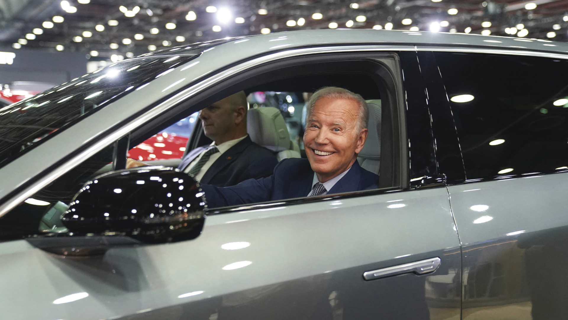 Joe Biden sitter i førersetet i en bil og smiler til kamera