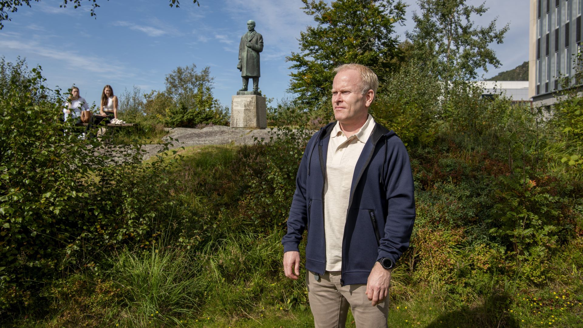 En mann som står ute i grønne omgivelser og ser utover.