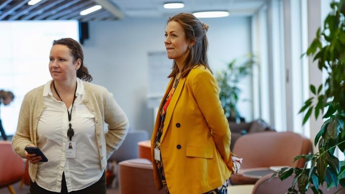 To kvinner som står i en samtale sammen i en konferansesal.