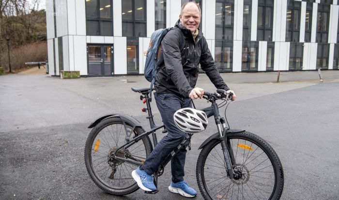 Mann på sykkel som smiler til kamera.