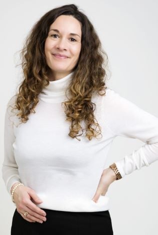 Kvinne som står oppstilt foran kamera og smiler forsiktig.