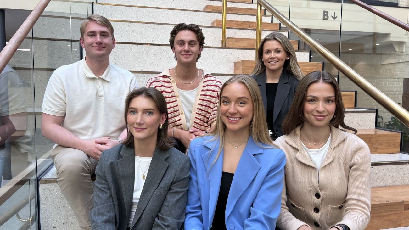 Seks studenter sitter i en trapp. Disse er medlemmer av studentutvalget i Econa i perioden 2025-2026
